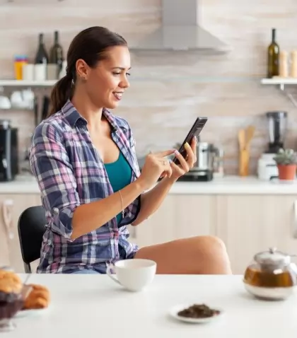 cheerful-woman-using-smarthphone-kitchen-during-breakfast-armoatic-green-tea_482257-8622