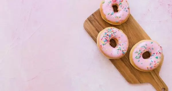 overhead-view-two-fresh-pink-donuts-wooden-chopping-board_23-2147909350